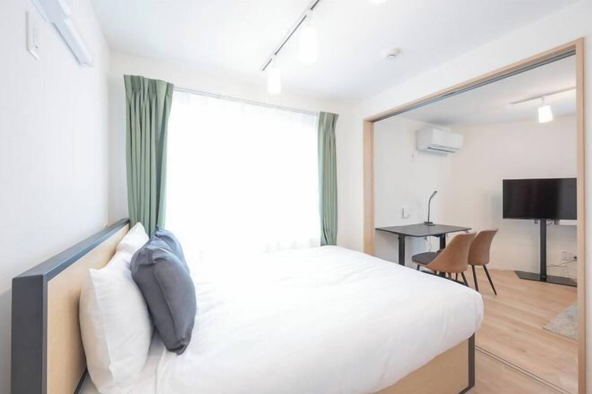 A hotel room with a bed, a desk, a chair, a TV, and a mirror.
