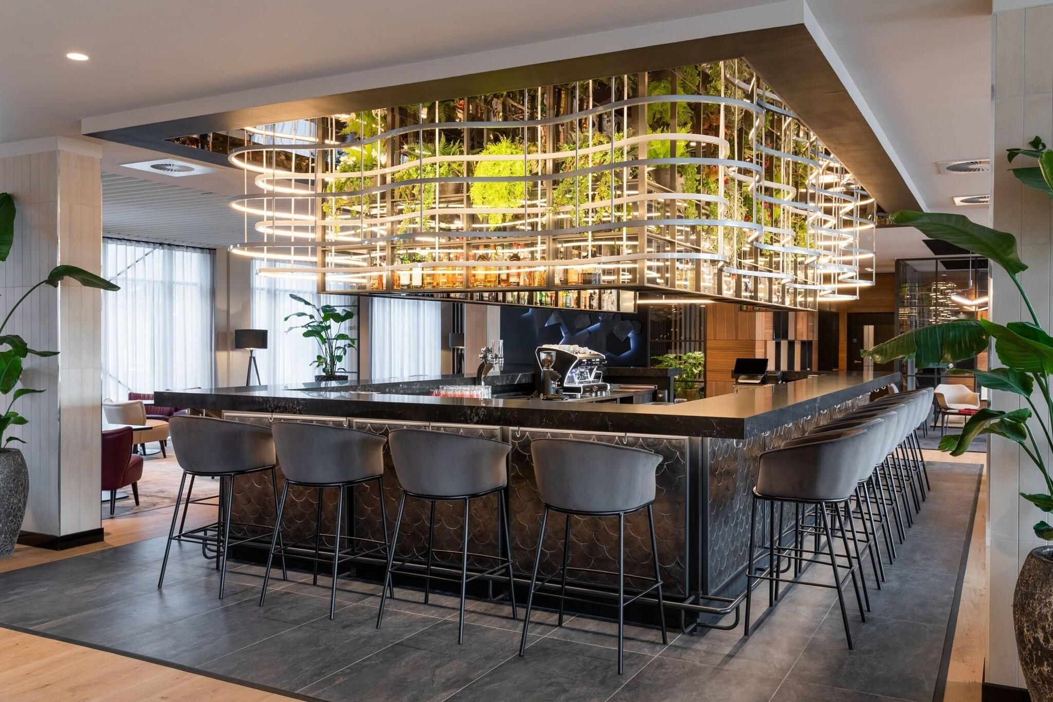 A modern bar area with a curved ceiling, bar stools, and a central bar counter.