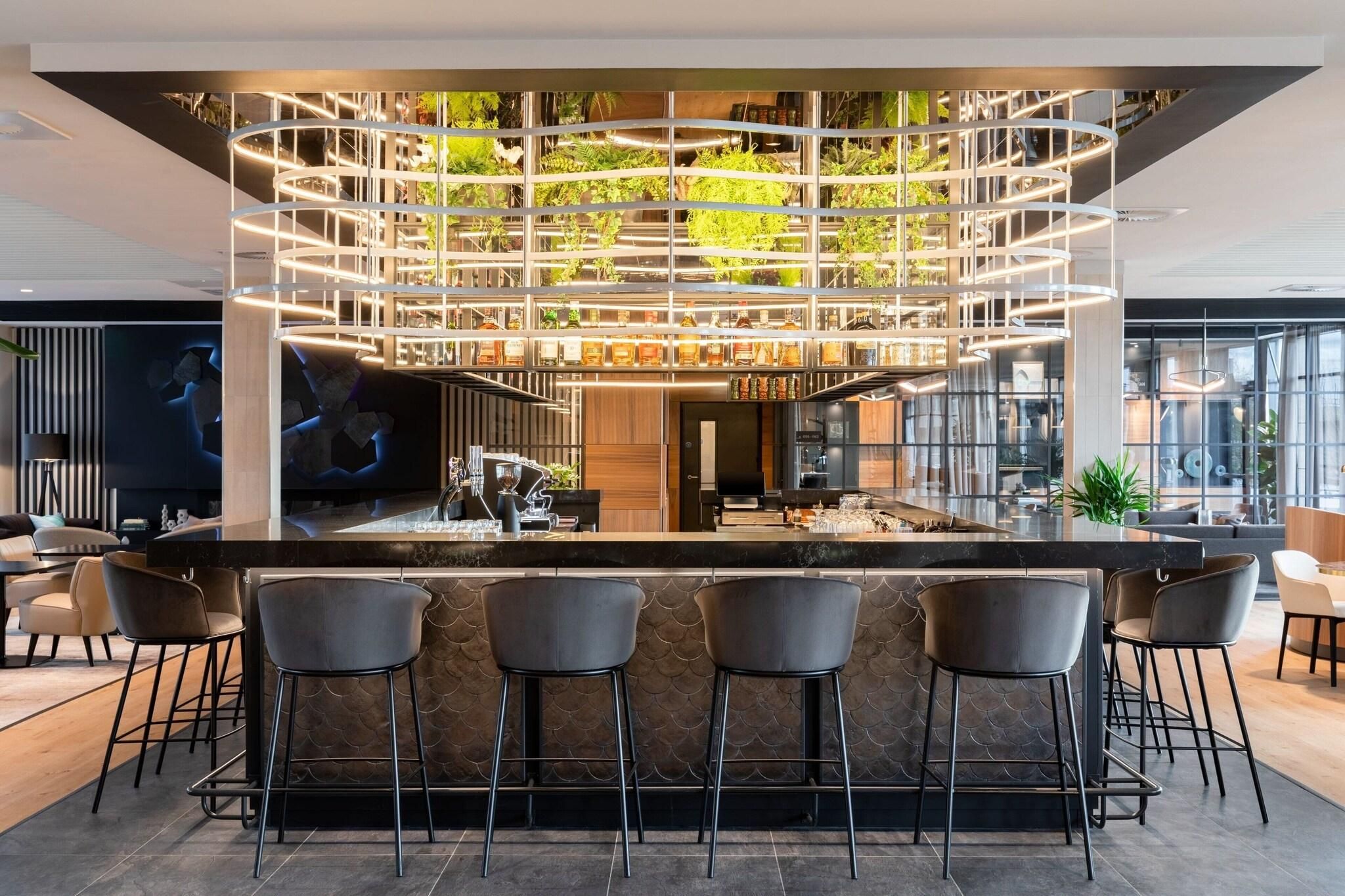 A modern bar area with a central island, bar stools, and a ceiling garden.