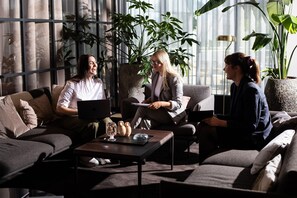 A modern living room with a sofa set, a coffee table with decorative items, and large windows with indoor plants. - Ac Hotel Inverness (Inverness)