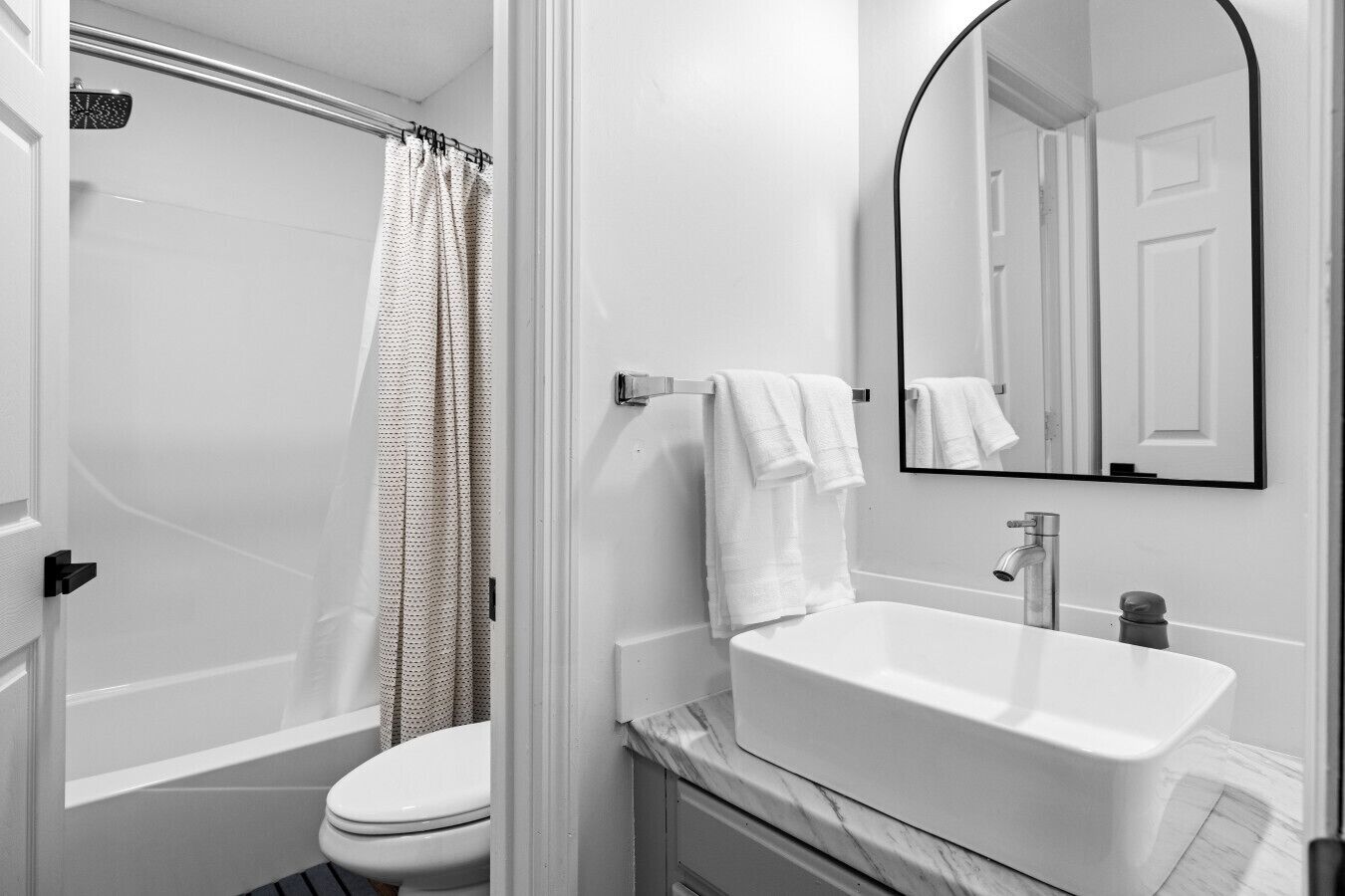 A bathroom with a white bathtub, a white sink, a toilet, and a shower curtain.