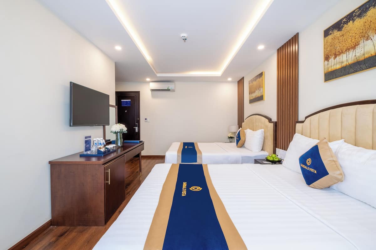 Una habitación de hotel con una cama, un escritorio, un televisor y un cuadro en la pared.