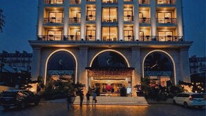 A multi-story hotel with a prominent entrance, balconies, and a well-lit facade. - Sandals Vista (1 Bao Loc)