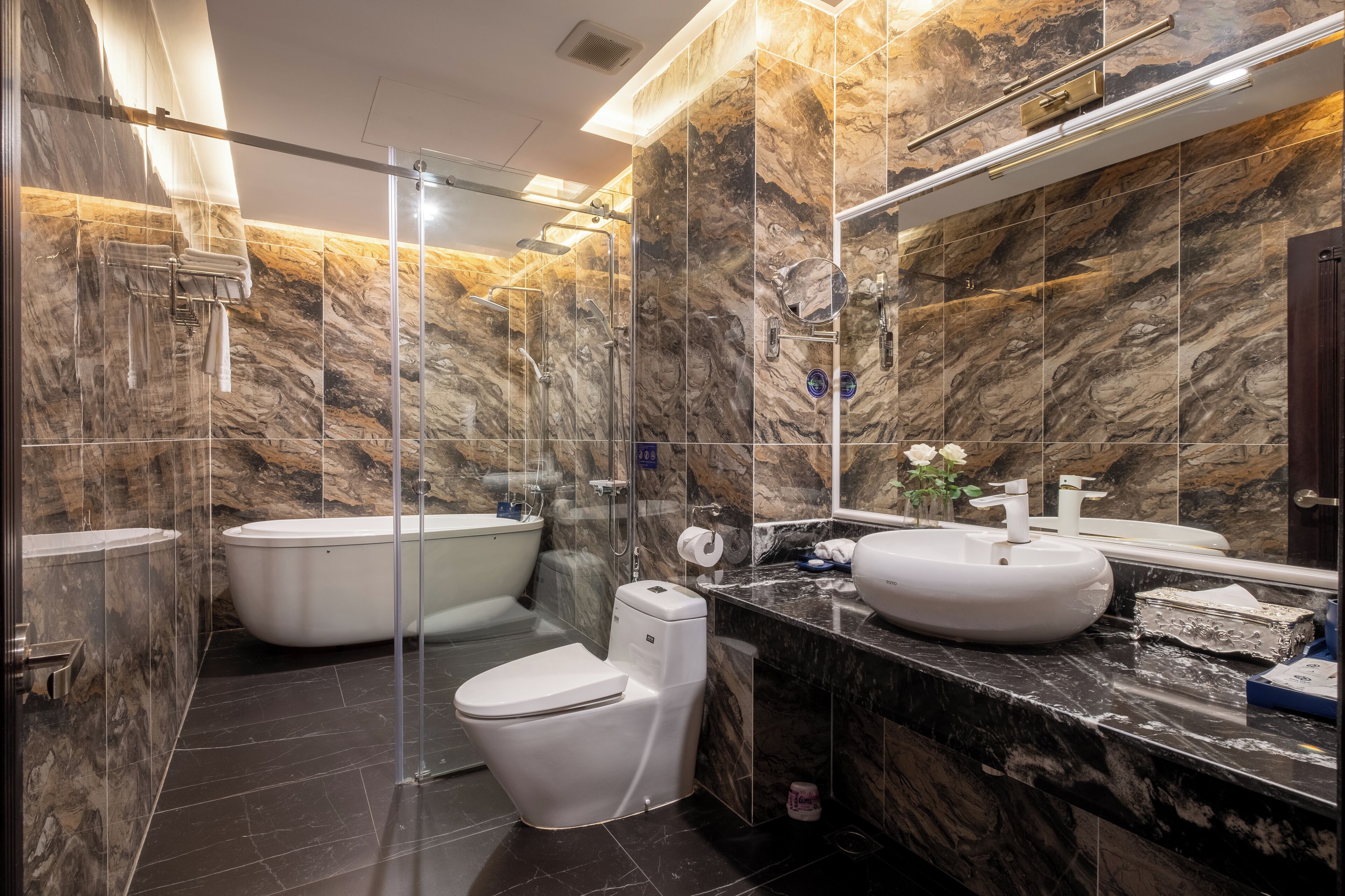 A modern bathroom with a glass-enclosed shower, a freestanding bathtub, a toilet, and a vanity with a sink and mirror.