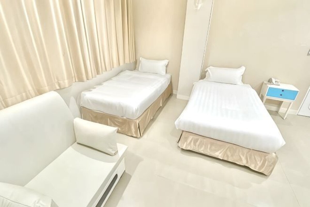 Une chambre d’hôtel avec deux lits, un canapé, une table de chevet et un miroir.
