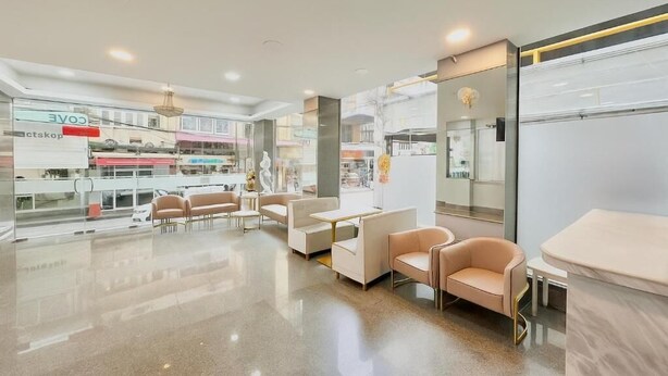A modern interior with seating areas, a glass wall with a view, and a reception desk. - ABCYQ Hotel (Bangkok)