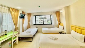 A hotel room with two beds, a desk, a TV, and a window with a city view. - ABCYQ Hotel (Bangkok)