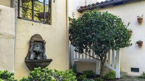A courtyard with a stone fountain, a tree, and potted plants. - Enjoy indoor-outdoor living, full kitchens and walk to beach and state st. (Santa Barbara)