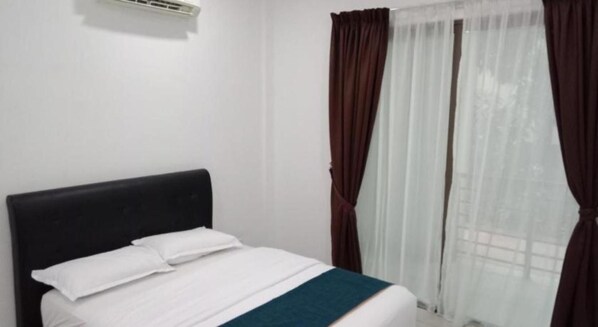 A single bed with a white mattress and pillows, a dark headboard, and a window with sheer white curtains and dark drapes. - AK Cvia Hotel (Padang Besar)