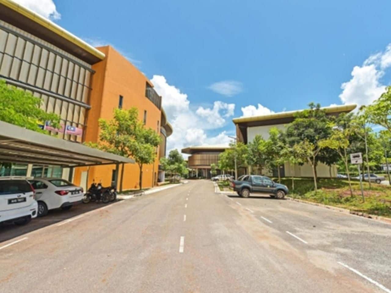 A street with parked cars and buildings on either side.