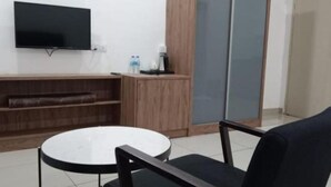 Una stanza moderna con TV a schermo piatto montata a parete, un tavolo rotondo con una sedia, un mobiletto in legno e una porta finestra scorrevole.