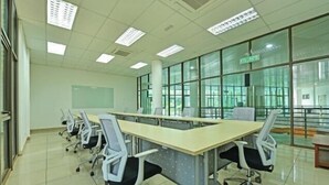 Una sala conferenze con un lungo tavolo, diverse sedie e ampie finestre.