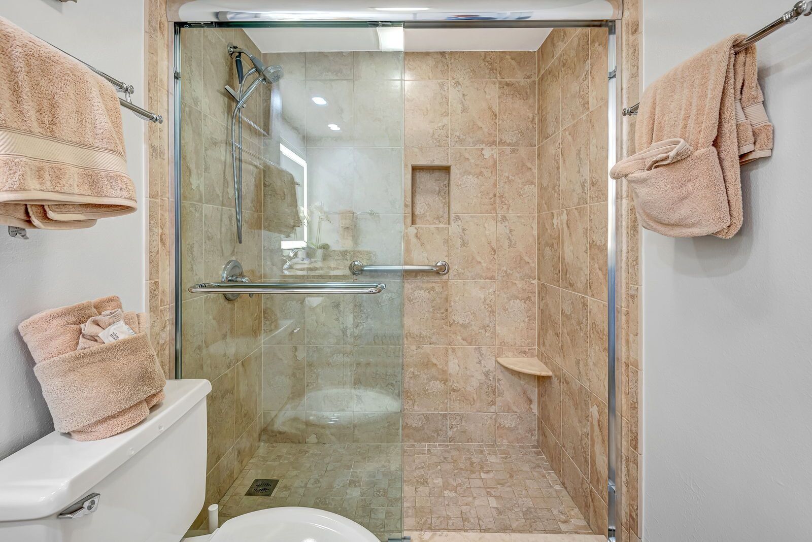 Cabina de dutxa amb vidre, amb aixeta de mà, barana de sujeció i paraigua per a tovalloles.