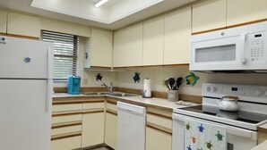 Eine kleine Küche mit Kühlschrank, Mikrowelle, Geschirrspüler und Herd.