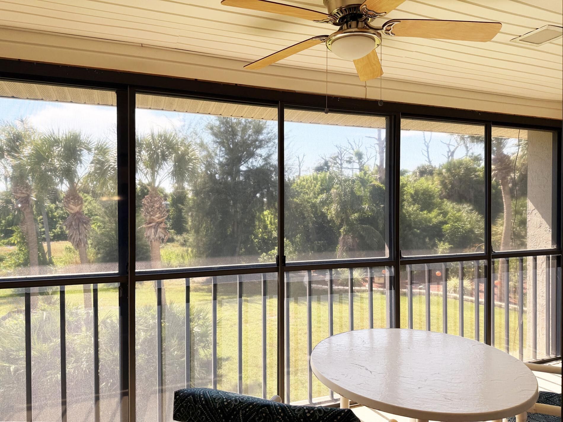 A room with a large window, a ceiling fan, and a round table.