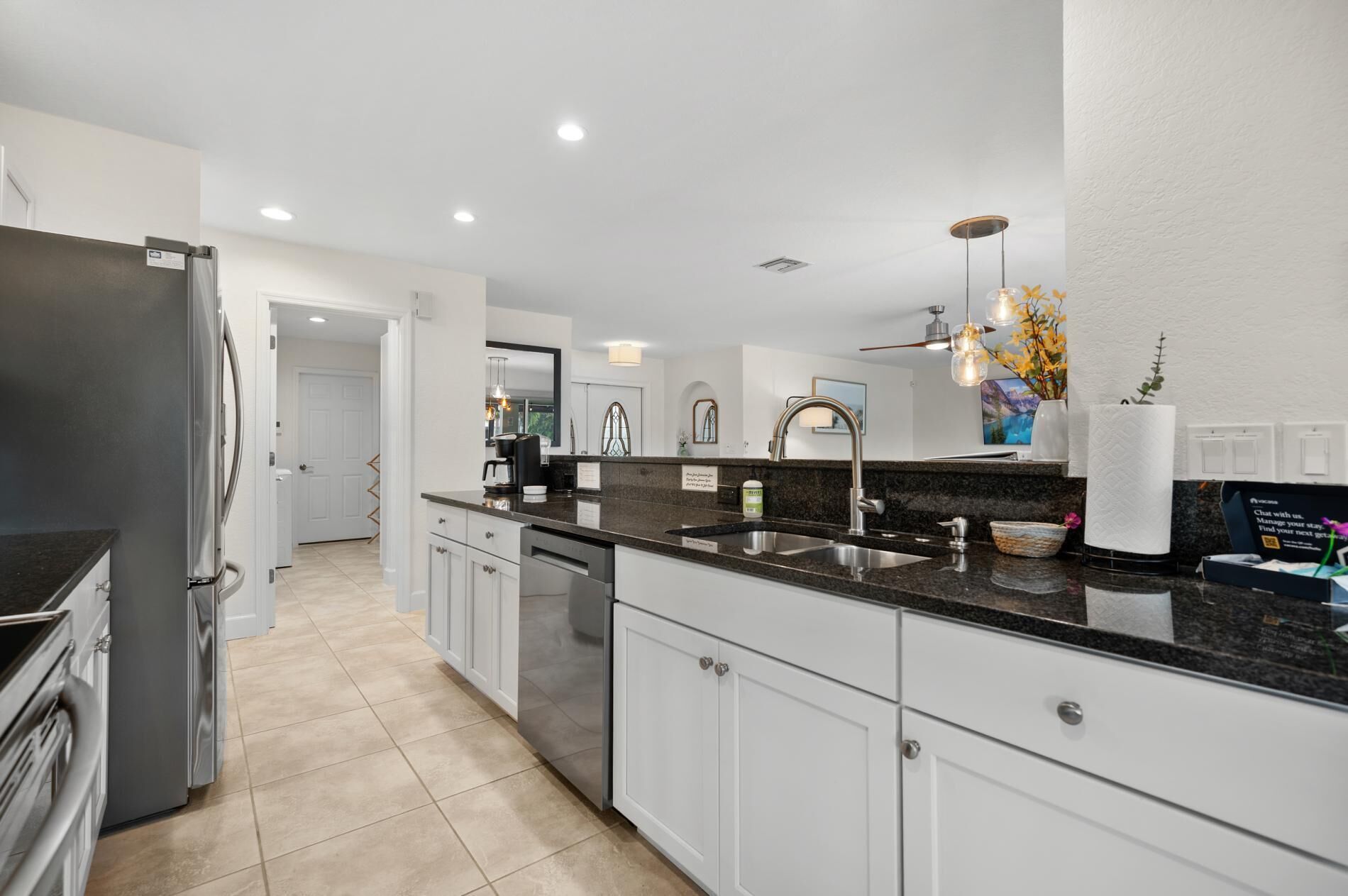 A modern kitchen with white cabinetry, a black granite countertop, and stainless steel appliances.