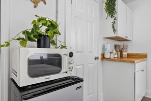 A compact kitchen with a built-in microwave and oven, a wooden countertop, and a hanging plant.