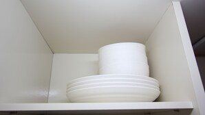 Um armário branco com uma pilha de pratos e tigelas brancos.