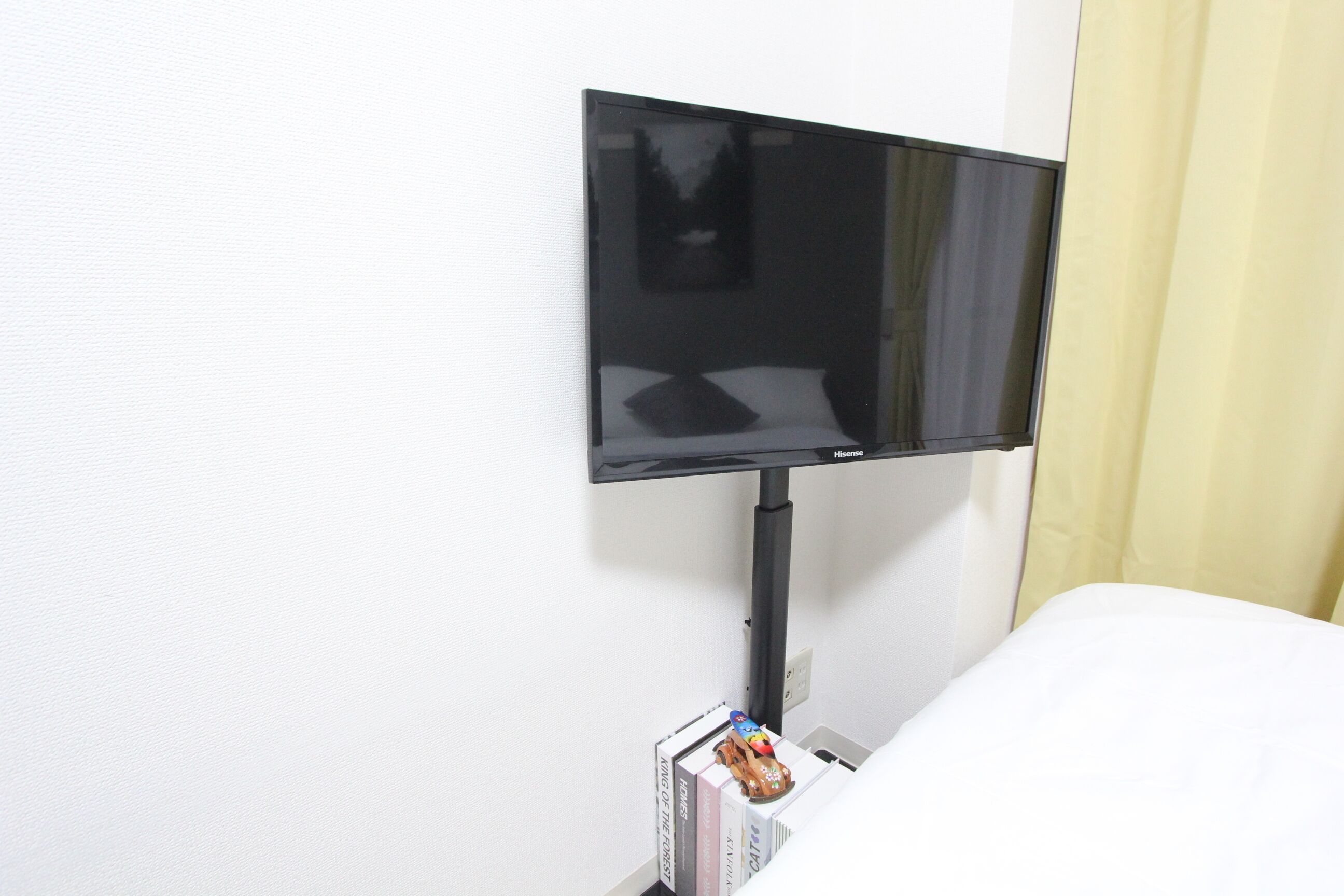 Televisão de tela plana fixada na parede de um quarto de hotel.