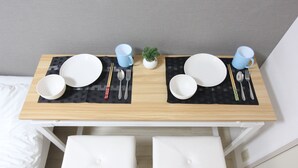 Uma mesa de jantar bem posta, com pratos, talheres e chávenas sobre um guardanapo xadrez.