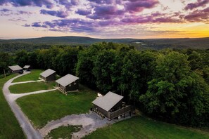Une propriété rurale comprenant plusieurs chalets, entourée d’une forêt dense et reliée par des chemins de gravier.