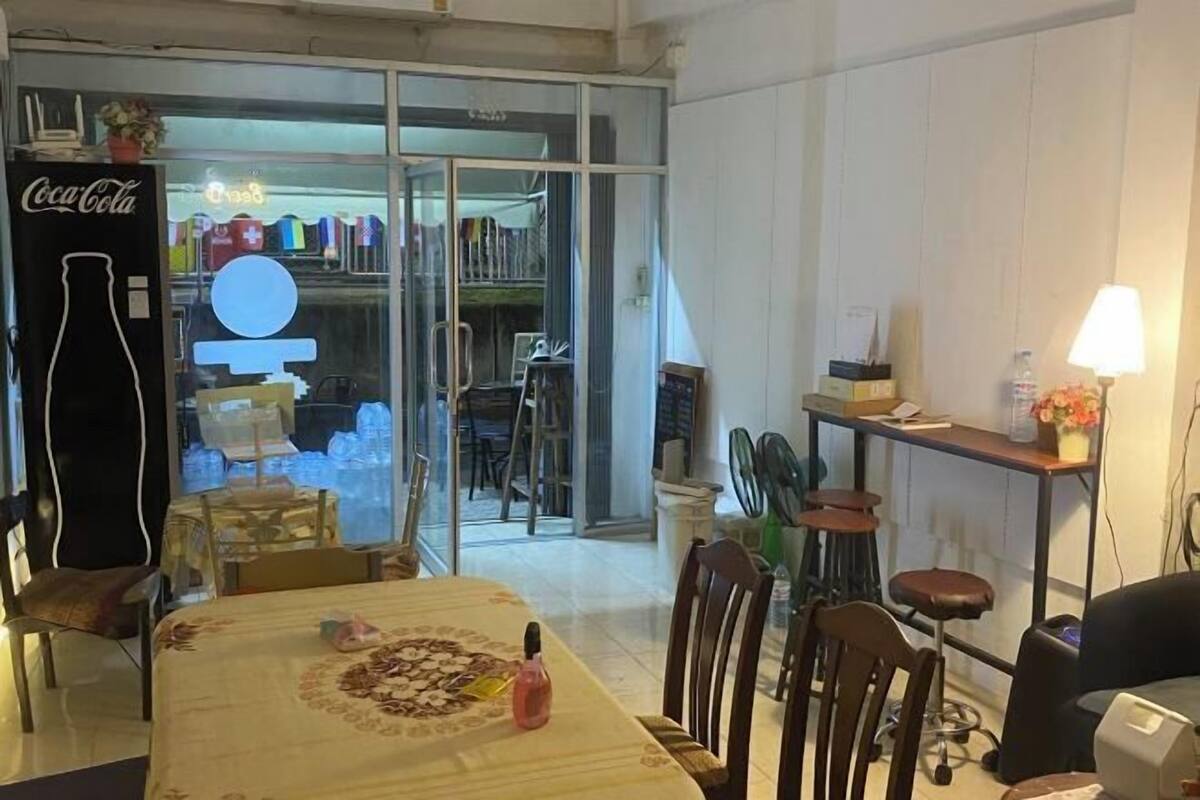 A dining area with a table set for two, a Coca-Cola sign, and a view of a store through glass doors.
