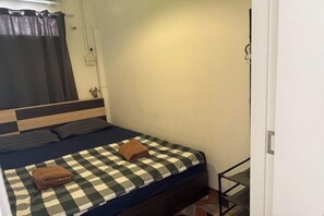 A single bed with a checkered bedspread, a brown towel, and a headboard with a wooden finish. - Sleep Break Hostel Sathon (Bangkok)