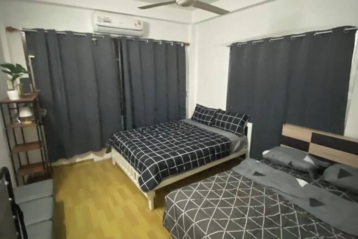 A bedroom with two beds, a ceiling fan, and a window with curtains.