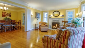 Una sala de estar amplia con chimenea, un comedor con mobiliario de madera y una zona de estar acogedora con cojines a rayas.