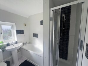 Ein Badezimmer mit einem weißen Waschbecken, einer Badewanne und einer Duschkabine.