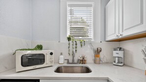 A modern kitchen with a built-in microwave, a coffee maker, and a sink. - Charming Hideaway Cottage Pensacola (Pensacola)
