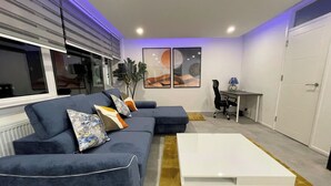 A modern living room with a sectional sofa, a white coffee table, and a desk with a chair. - Apartment - Sleeps 6 - Parking - WiFi (Guildford)