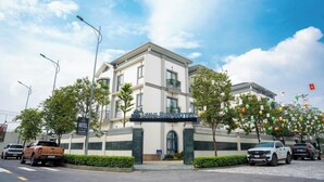 Un hôtel doté d’une entrée imposante, de plusieurs étages et offrant une vue sur un ciel dégagé.