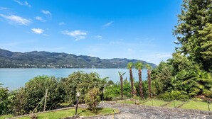 A view of a lake with mountains in the background, surrounded by lush greenery and palm trees.
