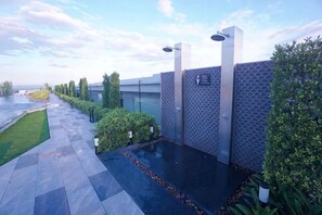Un espace piscine aménagé sur le toit, avec un mur aux motifs géométriques, une fontaine et un ciel dégagé.