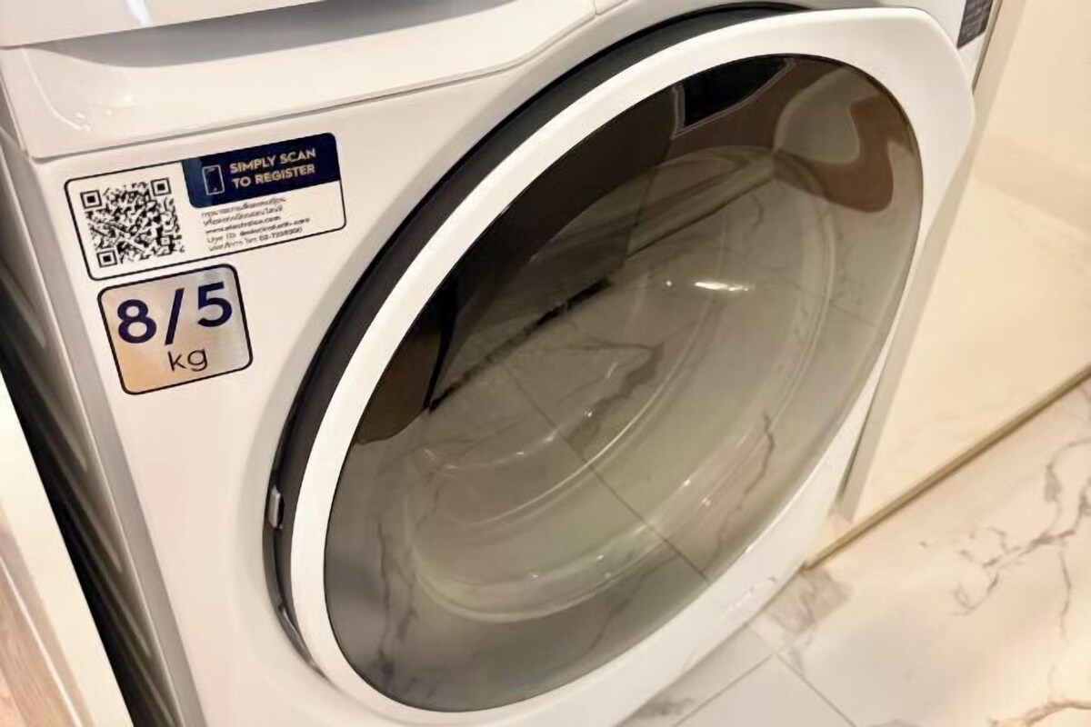 Een voorzichtszicht van een witte wasmachine met een QR-code en een label dat een capaciteit van 8/5 kg aangeeft.