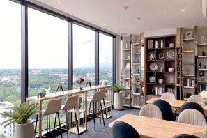 Een modern interieur met grote ramen, een bar en een verzameling boekenplanken.