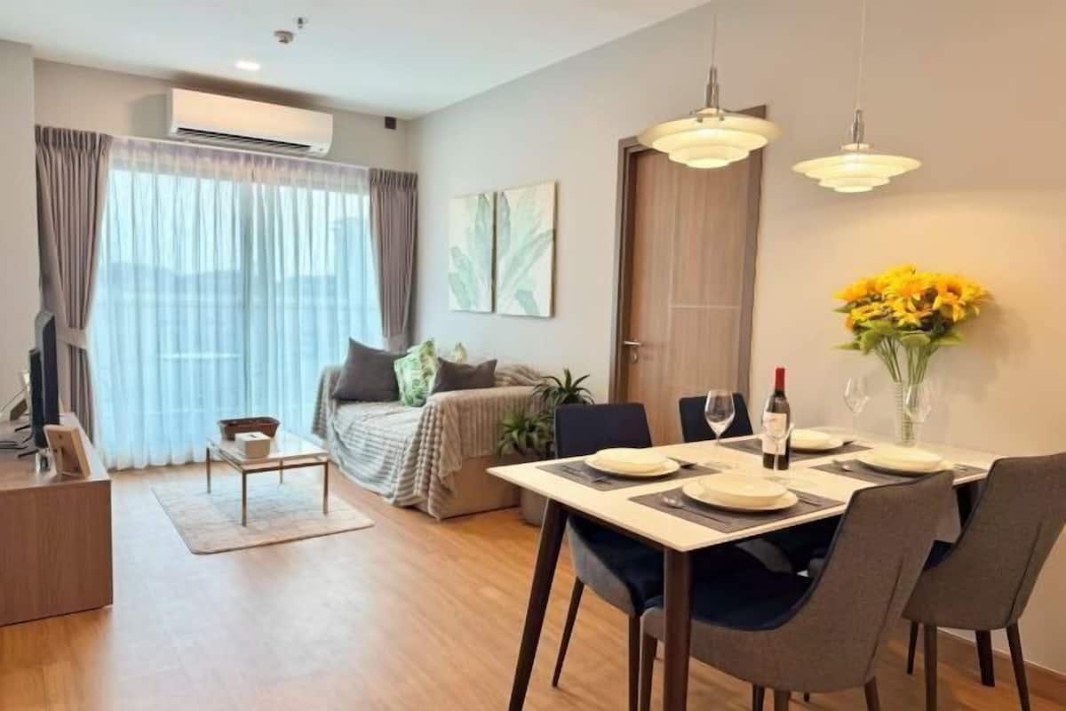 A modern living room with a dining area, a sofa set, a coffee table, and a large window with curtains.