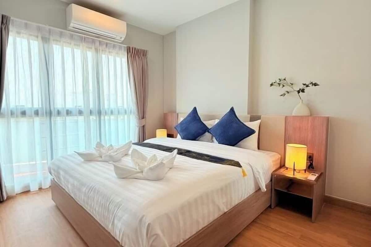 A hotel room with a bed, a nightstand, a lamp, and a vase with a plant.