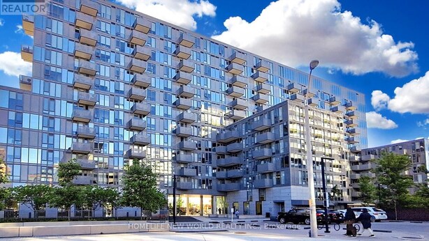 A modern multi-story building with a glass facade, balconies, and a gated entrance.