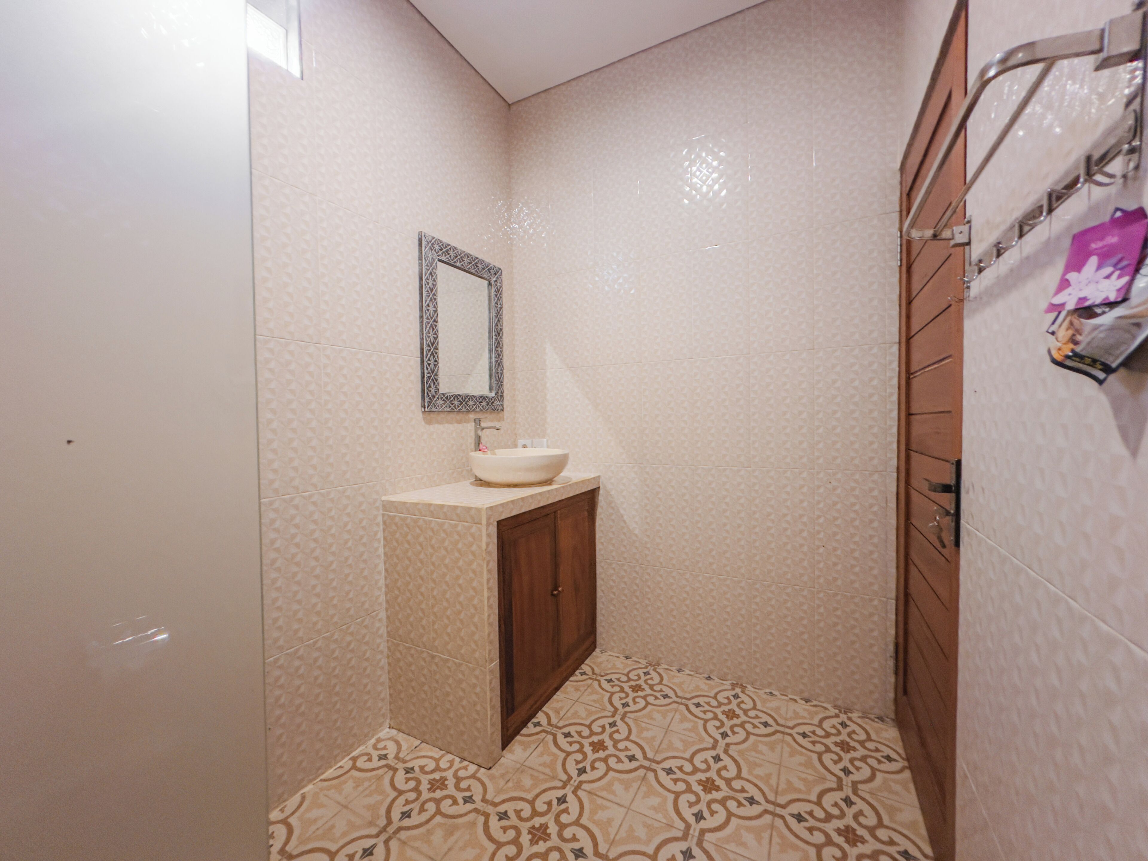 A small bathroom with a sink, mirror, and patterned floor tiles.