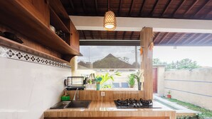 Une cuisine avec des meubles de rangement en bois, une cuisinière à gaz, un évier et un luminaire suspendu.