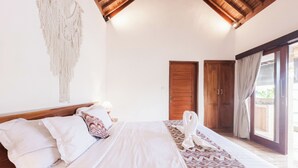 Une chambre à coucher avec un lit, une tête de lit en bois, une décoration murale en macramé et une couvre-lit à motifs.