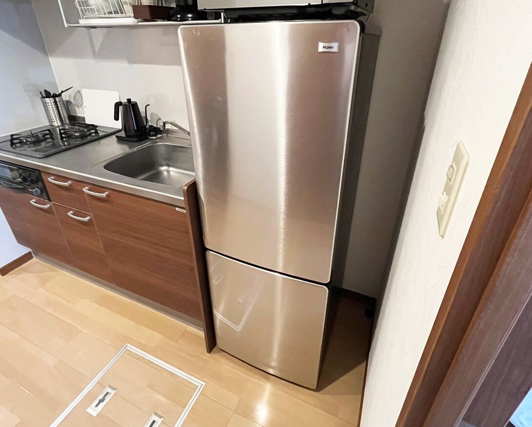 A kitchen with a stainless steel refrigerator, a gas stove, and a sink.