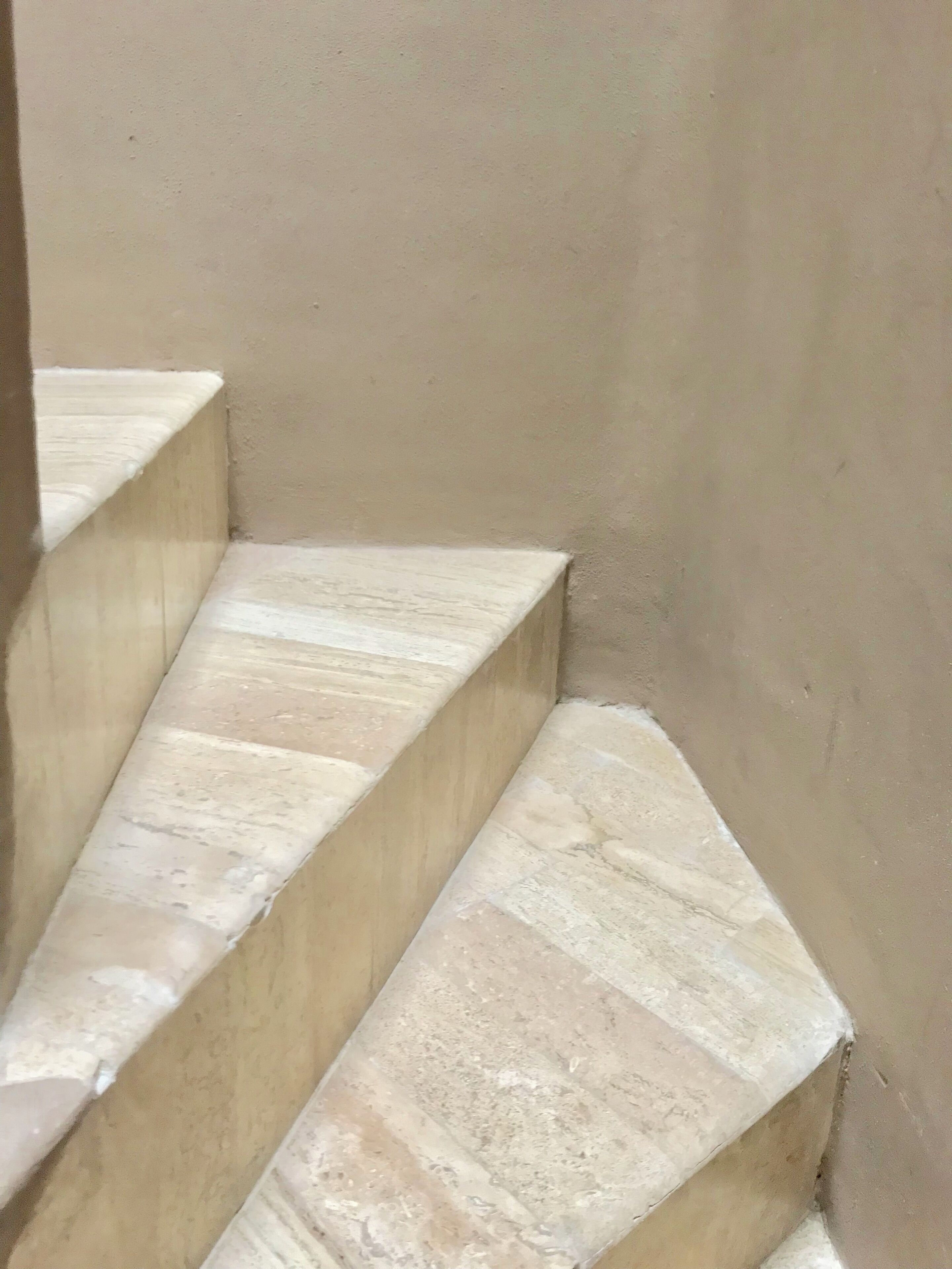 A set of beige stone steps leading up to a landing.