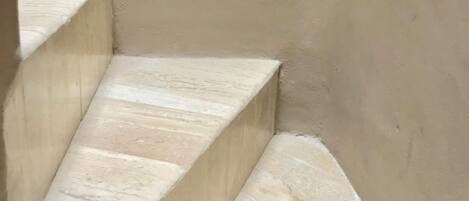A set of beige stone steps leading up to a landing.