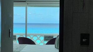 A room with a bed, a view of the ocean, and a balcony with chairs. - OvaCancun Apartments (Cancun)