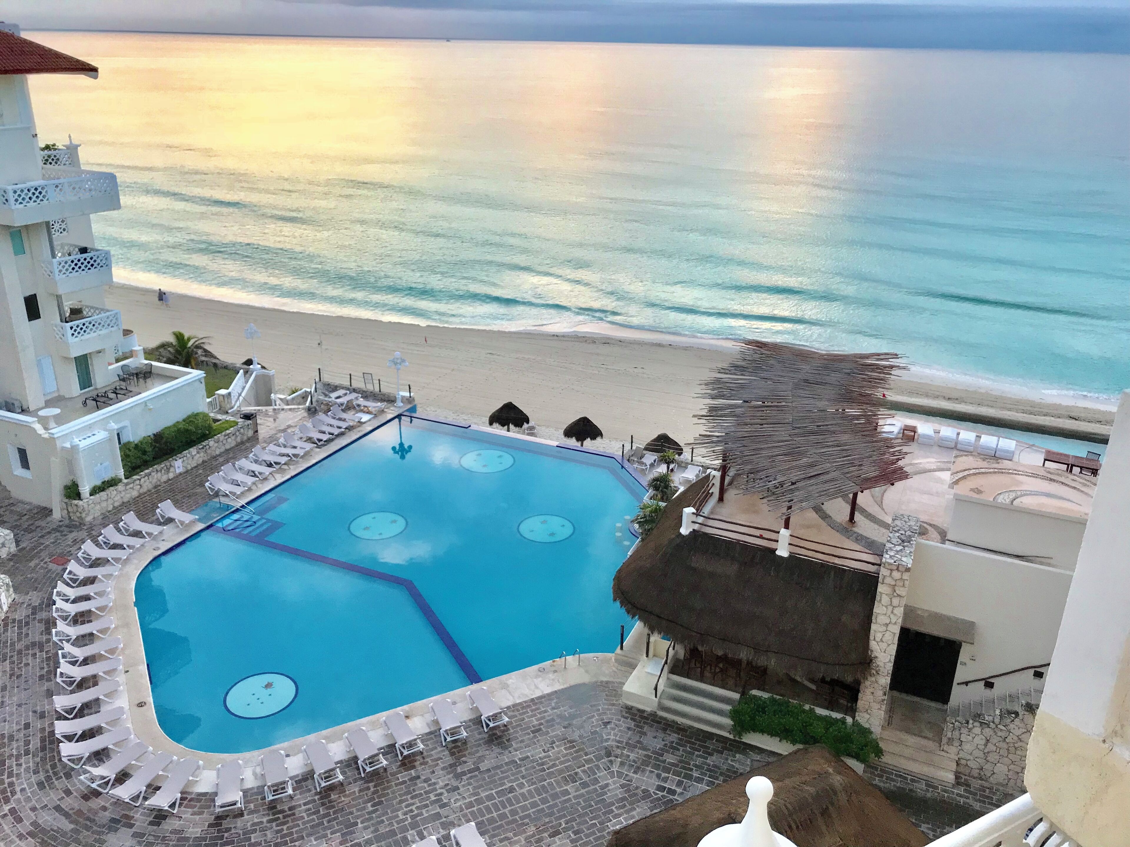 Ein Pool mit Liegestühlen, ein Strand und ein Gebäude mit einem Balkon.