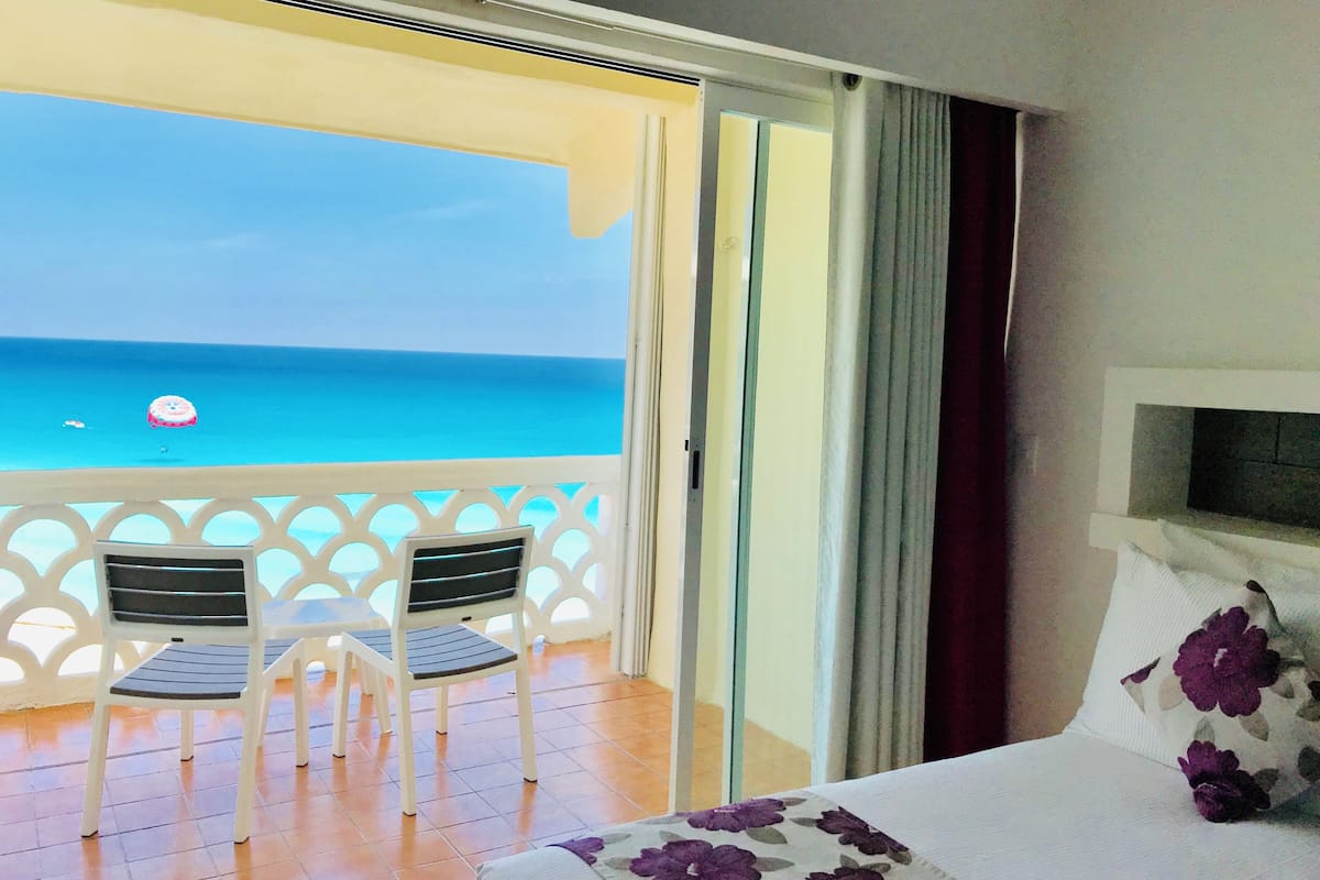 Ein Balkon mit zwei Stühlen und einem Bett mit floralen Kissen.
