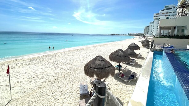 A beachside hotel with a pool, beach umbrellas, and a clear view of the ocean. - OvaCancun Apartments (Cancun)